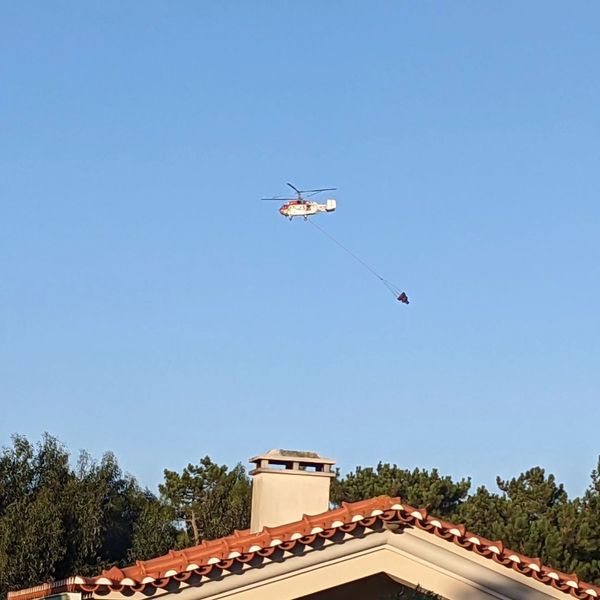 Firefighting helicopter going to get water from the ocean to dump on a forest fire nearby