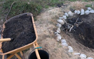 Mixing biochar into a pile of compost to charge it.