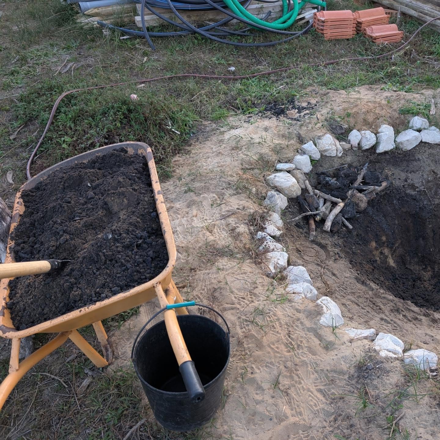 Mixing biochar into a pile of compost to charge it.