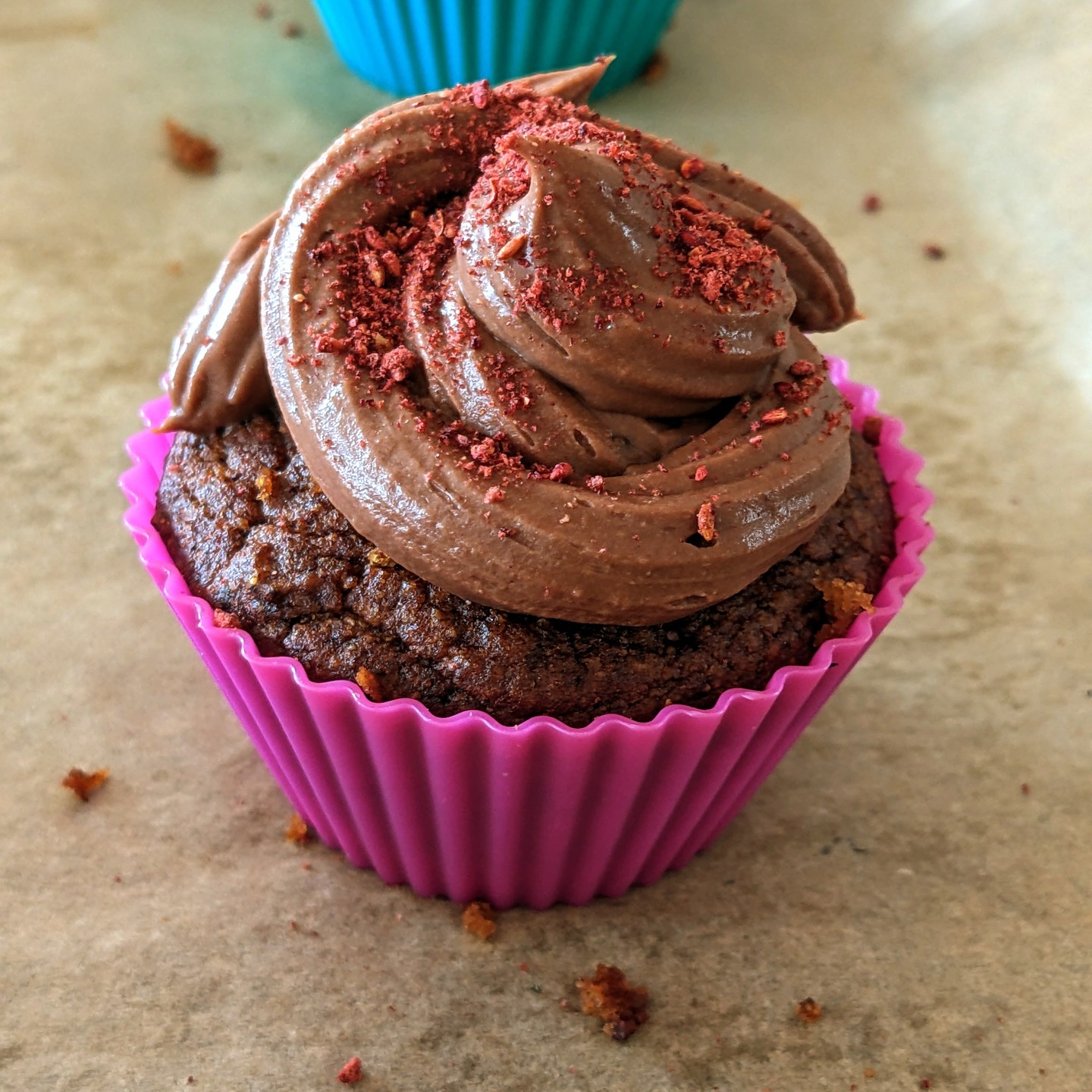 Berry Cupcake. Delicious, nutritious. It is plant based and refined sugar free. That powder on top is raspberry. A “chocolate” frosting and blueberry filling.