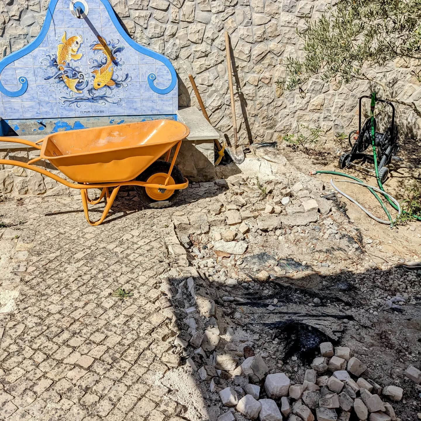 Dismantling damaged section of calçada around the decorative fountain in #zone1.