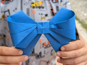 Child holds an origami bow